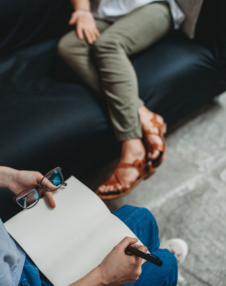 In-Person Mental Health Therapy Session | Mount North Close-up of a mental health therapy session, featuring a client with a notebook and a therapist listening actively.
