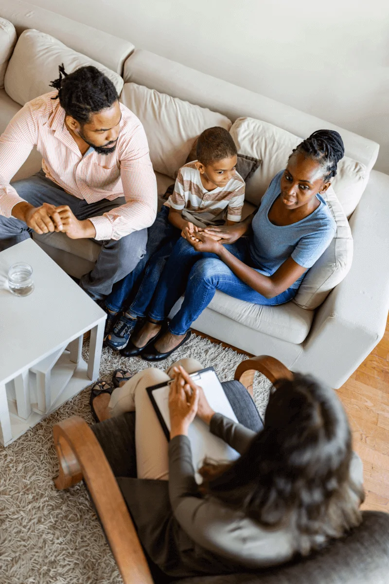 A family in a co-parenting therapy session, discussing strategies to improve communication and child well-being.