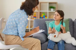 A young girl smiles while speaking with a psychologist during a child-focused psychological evaluation in a custody case.