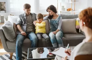 A family in a reunification therapy session with a counselor, helping a young boy reconnect with his parents in a safe and supportive environment.