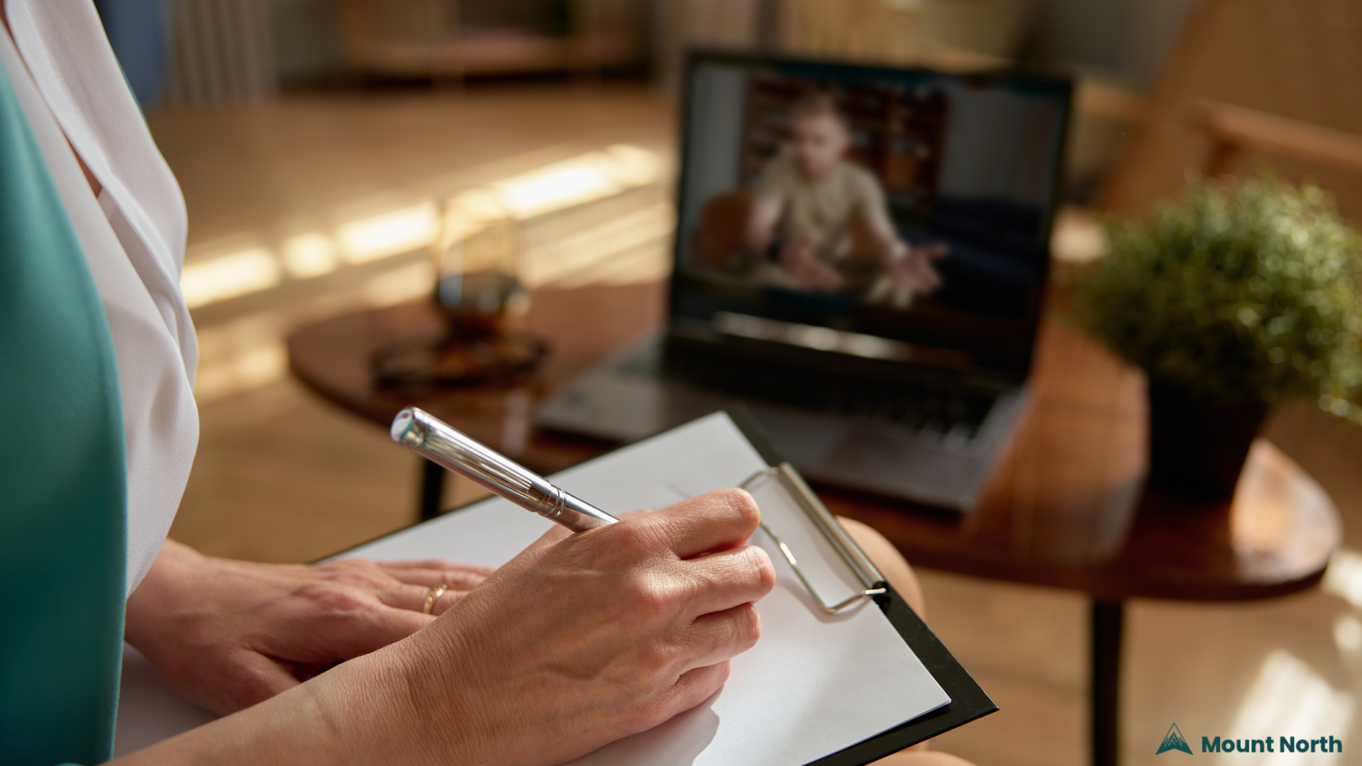 Online Medication Management – Mount North Telehealth Services Close-up of a mental health provider taking notes during a telehealth video session, representing online psychiatric medication management at Mount North.